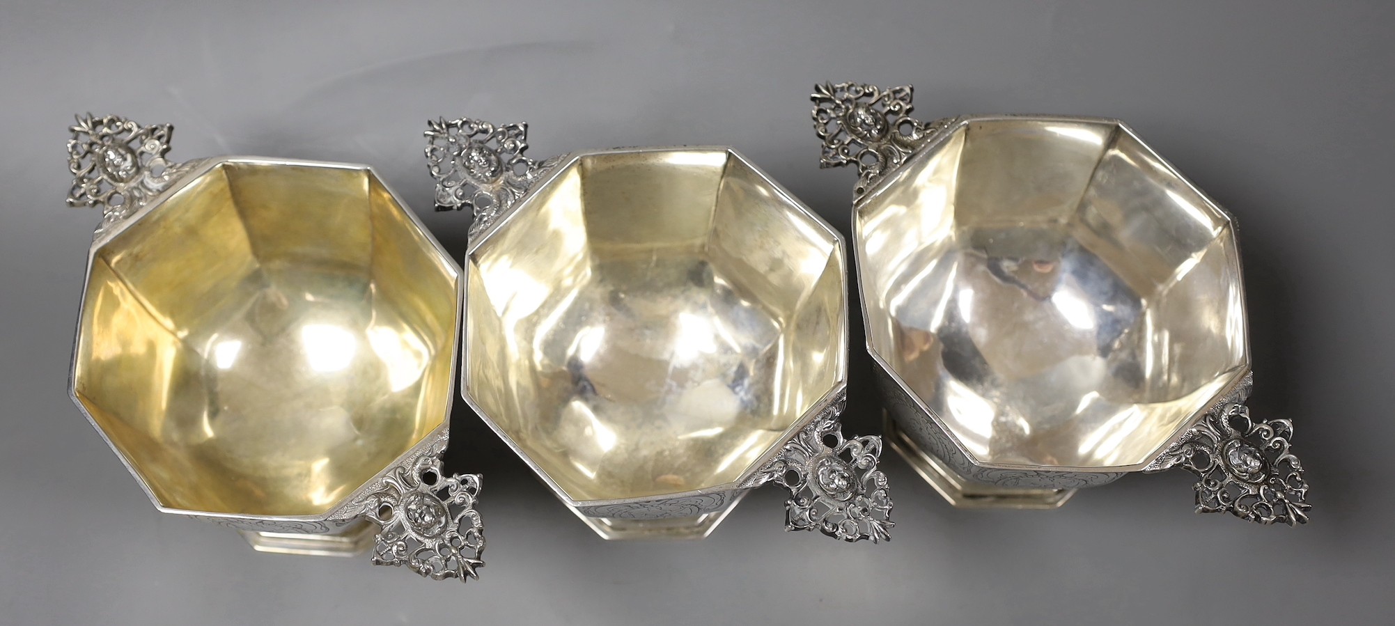 A set of three 19th century Dutch 833 standard white metal octagonal twin mask handled octagonal pedestal bowls, height 10cm, 35.9 oz.